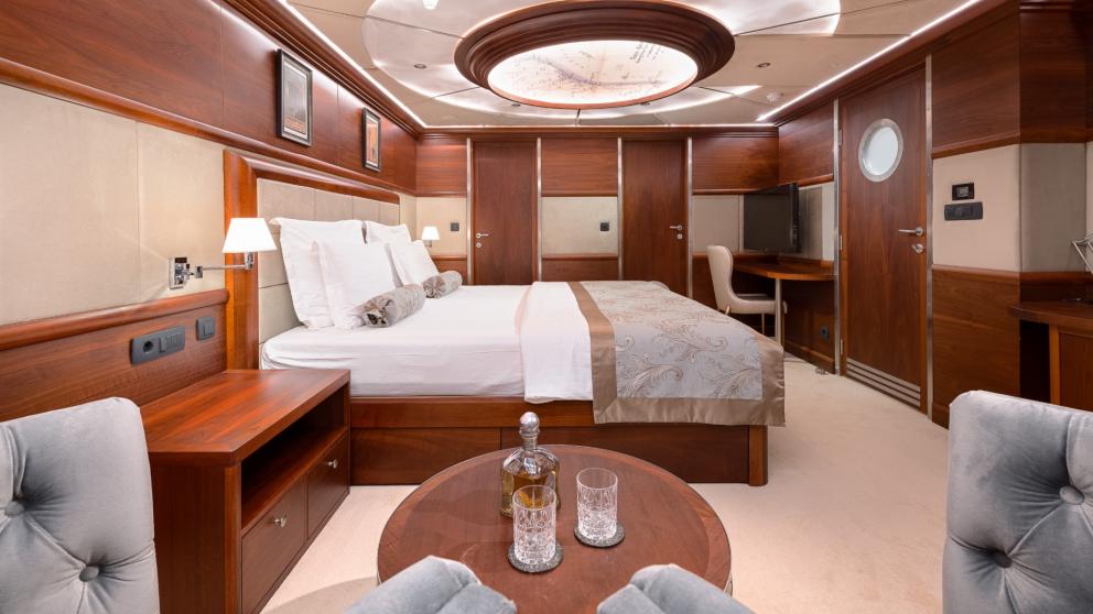 Ein Luxus Schlafzimmer mit Doppelbett, Sitzecke und Kommoden besticht durch eine riesige runde Glaslampe an der Decke